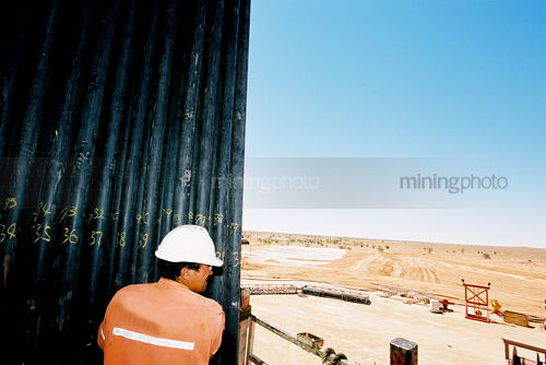 Drill rig worker stacking pipe on the platform - Mining Photo Stock Library