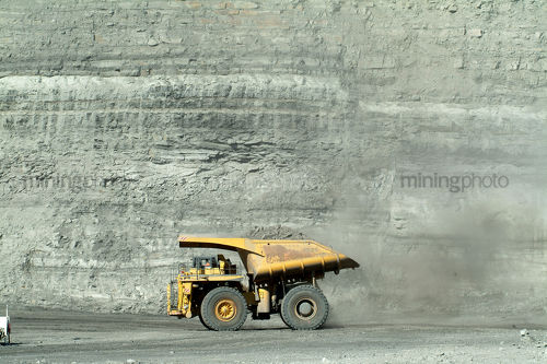 Loaded haul truck moving with opencut high walls behind - Mining Photo Stock Library