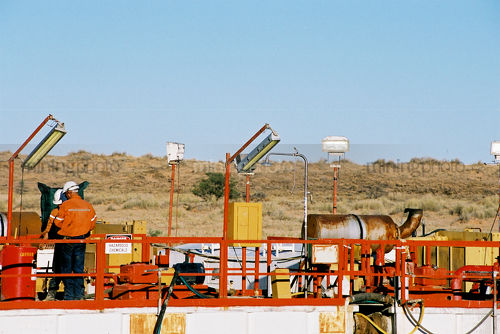 Drill rig workers in full PPE working on the drill rig site in the desert. - Mining Photo Stock Library