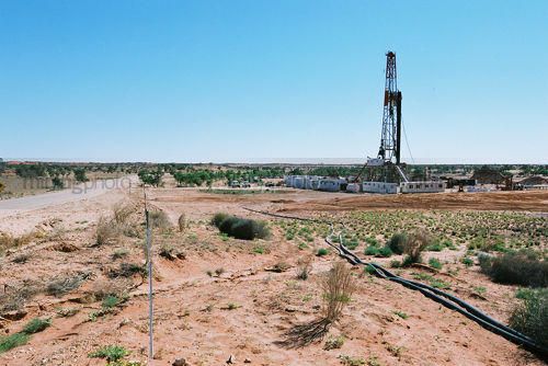 Drill rig in the desert with vegetation and sandy soil in foreground - Mining Photo Stock Library