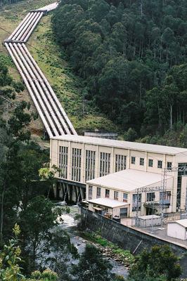Hydro power plant with water pipes leading back up the hill.  plant is on a river. - Mining Photo Stock Library