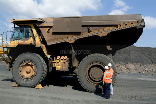 Female truck driver being instructed by mine worker.  standing next to large haul truck. - Mining Photo Stock Library