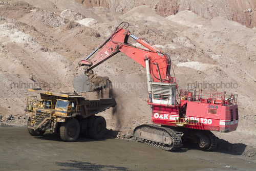 Excavator loading a haul tuck on opencut mine site. - Mining Photo Stock Library