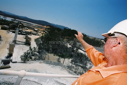 Mine supervisor looking out over the processing plant and tailings dam from atop the high conveyor.  shot from the side. - Mining Photo Stock Library