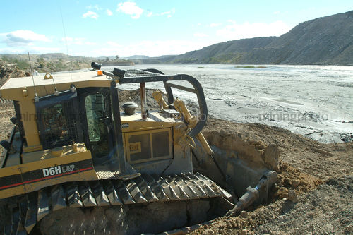 Swamp bulldozer pushing dirt to cover coal tailings dam - Mining Photo Stock Library