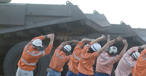 Truck drivers in PPE doing morning stretching together before shift.   - Mining Photo Stock Library