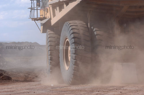 Haul truck turning in a cloud of dust on a mine site road.  shot close - Mining Photo Stock Library