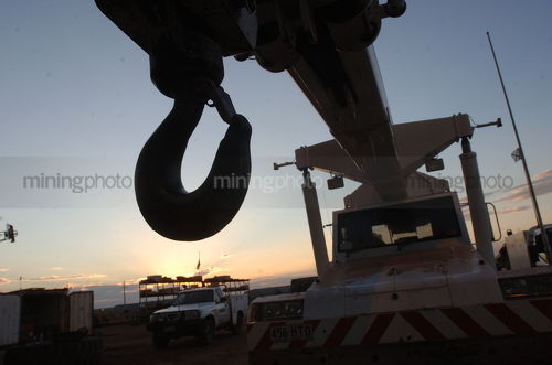 Silhouette of crane hook on mine site at sunset - Mining Photo Stock Library