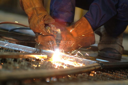 Close up of workers gloved hands using a welder - Mining Photo Stock Library