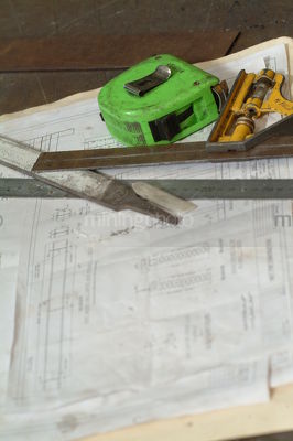 Tape measure and engineering plans with other implements in workshop. - Mining Photo Stock Library