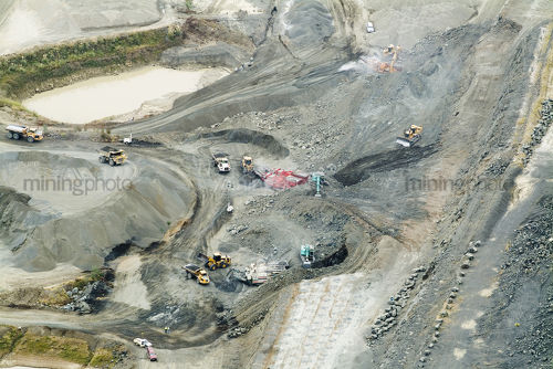 Aerial of quarry in action with loaders bulldozers and lots of machinery working. - Mining Photo Stock Library