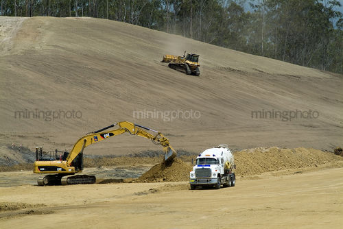 Excavator, bulldozer and water cart working on a highway construction site. - Mining Photo Stock Library