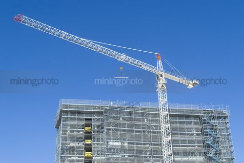 Crane on building site with blue sky behind. very clean shot. - Mining Photo Stock Library