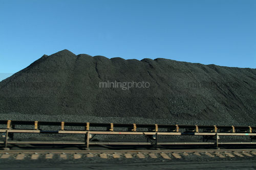 Stockpiled coal with moving conveyor in foreground - Mining Photo Stock Library