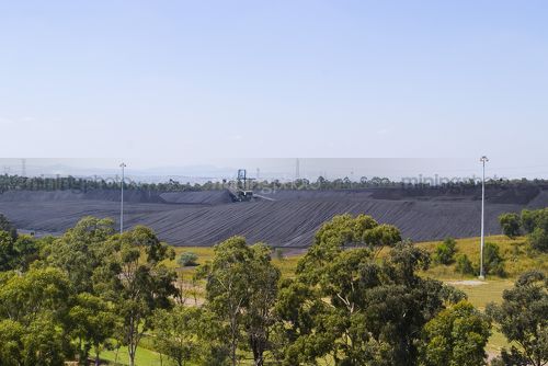 Coal stacker stockpiling with green trees in foreground. good sustainability image. - Mining Photo Stock Library