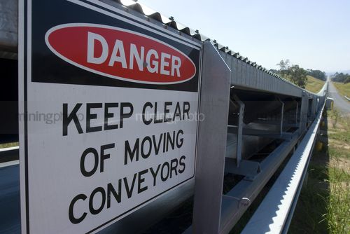Covered coal conveyor with safety sign in foreground  - Mining Photo Stock Library