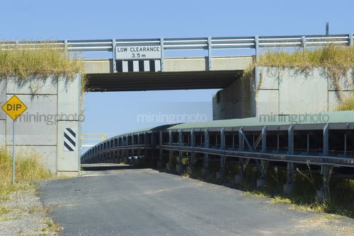 Covered overland conveyor with vehicle bridge above - Mining Photo Stock Library