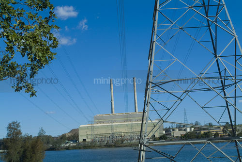 Power station in background with lake and electricity tower in foreground. - Mining Photo Stock Library