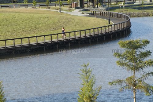 Jogger on circular waterfront lake  with green grass behind.  new subdivision property shot. - Mining Photo Stock Library