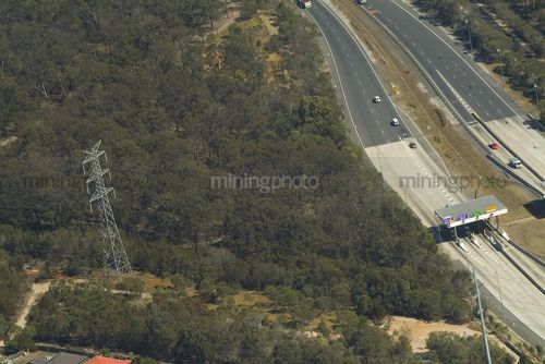 Vehicle toll booth and station on a highway with electricity tower and power lines nearby in bush.  - Mining Photo Stock Library