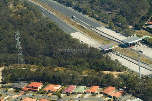 Vehicle toll booth and station on a highway with electricity tower and power lines nearby in bush. residential houses adjacent. - Mining Photo Stock Library