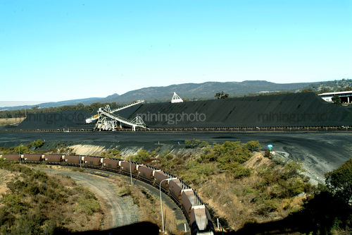 Heavy rail carriages with stockpiled coal and coal track loader behind.  aerial image - Mining Photo Stock Library