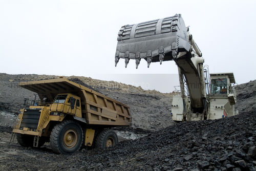 Excavator loading coal from the open cut seam floor into a haul truck.  shot up close. - Mining Photo Stock Library