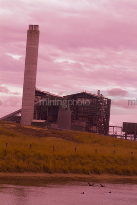 Smokestack of power station shot at sunset looking opver the lake. vertical shot. - Mining Photo Stock Library