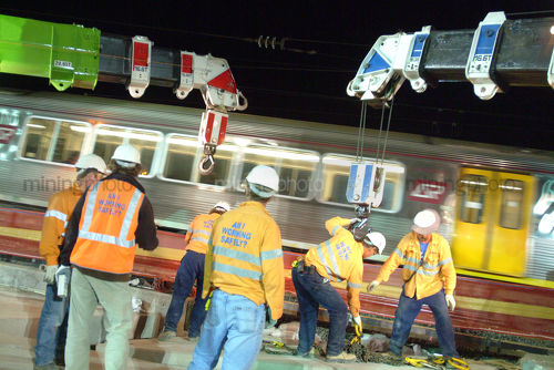 Rail track workers in full PPE with light rail going past next to them. lots of movement from the train. - Mining Photo Stock Library