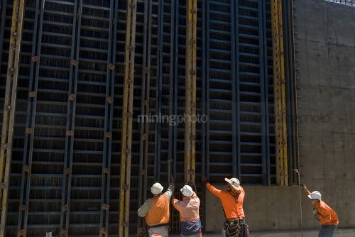 Construction workers on infrastructure site lift concrete form work into place with crane. - Mining Photo Stock Library