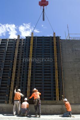 Construction workers on infrastructure site lift concrete form work into place with crane. - Mining Photo Stock Library