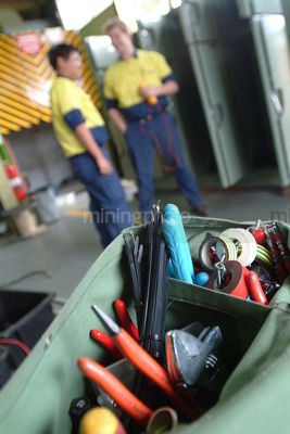 Maintenance worker's tool belt with workers out of focus in background. vertical shot. - Mining Photo Stock Library