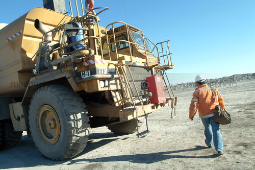 Female worker arriving at large water cart on mine site. - Mining Photo Stock Library