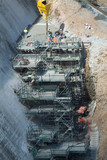 Mining Photo Stock Library - complex platform scaffolding attached to dam wall construction site.  workers in PPE pouring concrete on top. ( Weight: 2  New Image: NO)