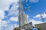 Mining Photo Stock Library - worker looking up at transformer tower and cooling tower at power station on bright blue sky day ( Weight: 1  New Image: NO)
