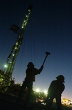Mining Photo Stock Library - Silhouette of 2 drill rig workers hammering with the lights of the  derrick behind at dusk. ( Weight: 1  New Image: NO)