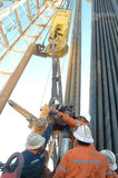 Mining Photo Stock Library - workers attaching equipment to the derrick on a drill rig ( Weight: 1  New Image: NO)