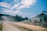 Mining Photo Stock Library - loaded haul truck leaving cloud of dust as it drives along road with conveyor stockpiling in background.  great shot.  ( Weight: 1  New Image: NO)