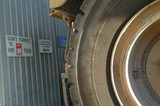 Mining Photo Stock Library - large mine haul truck parked next to safety signs at workshop. truck shot close so only wheel and tyre is seen. ( Weight: 5  New Image: NO)