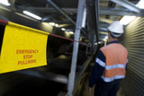 Mining Photo Stock Library - worker in PPE walking next to covered conveyor with safety warning sign in foreground.  ( Weight: 4  New Image: NO)