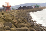 Mining Photo Stock Library - reclaimers stockpiling coal at terminal with ocean surf pounding rock retaining wall in foreground.  shot from rock wall. ( Weight: 1  New Image: NO)