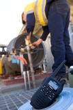 Mining Photo Stock Library - radio walkie talkie up close with worker out of focus in background. iniden signage can be removed. ( Weight: 3  New Image: NO)