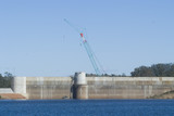 Mining Photo Stock Library - construction crane working on a dam wall. shot from the water side with a maintenance boat at the base of the wall. ( Weight: 4  New Image: NO)
