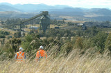 Mining Photo Stock Library - two mine workers in PPE walk down hill at wash plant. distant shot of coal wash plant with rail and mountains in background.  good revegetation example in foreground. ( Weight: 1  New Image: NO)