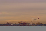 Mining Photo Stock Library - plane about to land at airport with shipping port and wharf loaders underneath and in background. great colours at sunset.  very clean shot, good panorama strip. ( Weight: 2  New Image: NO)