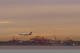 Mining Photo Stock Library - plane about to land at airport with shipping port and wharf loaders underneath and in background. great colours at sunset.  very clean shot, good panorama strip. ( Weight: 2  New Image: NO)