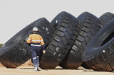Mining Photo Stock Library - mine worker in full PPE walking past stockpile of truck tyres.  person is on kleft hand side of frame. plenty of space to the right for copy. ( Weight: 1  New Image: NO)