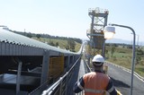 Mining Photo Stock Library - Mine worker in full PPE on walkway next to moving covered overland coal conveyor.  overland conveyor stretched to horizon. ( Weight: 1  New Image: NO)