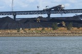 Mining Photo Stock Library - two dozers stock piling coal at wharf terminal.  overhead conveyor in background.  sea water in foreground. ( Weight: 1  New Image: NO)