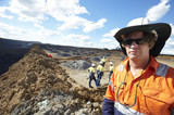 Mining Photo Stock Library - mine site worker looking straight at the camera in open cut mine.  team workers pointing and working behind.  camera framed for double page spread. ( Weight: 1  New Image: NO)